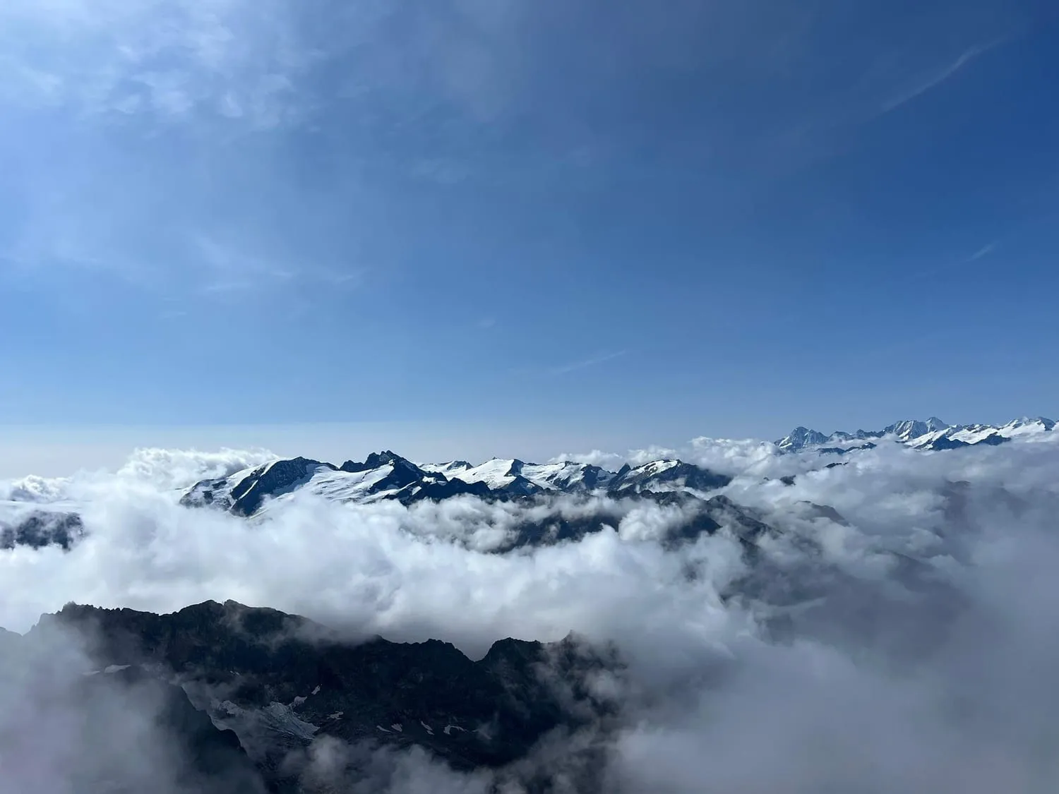 Dark mountain ridges rising out of an unbroken sea of cloud.
