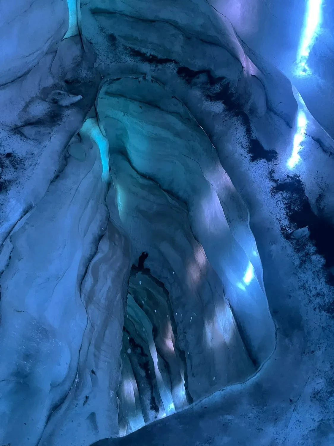 Deep blue ice inside a glacier, streaked with darker bands.