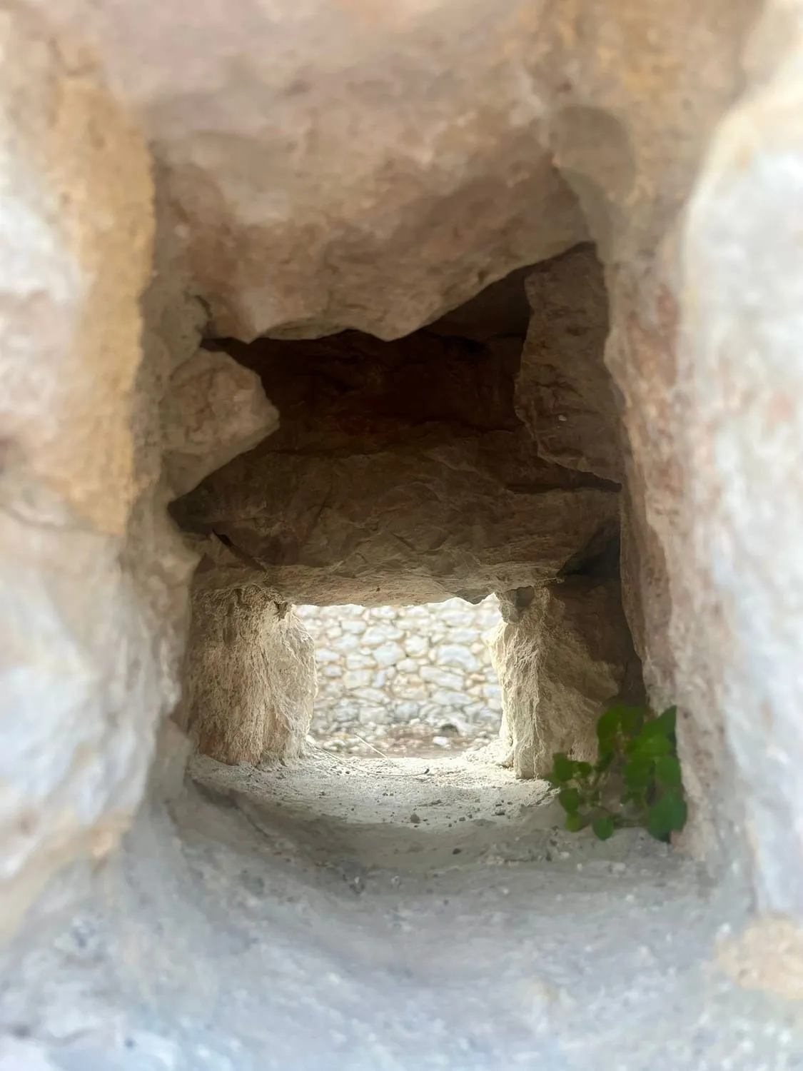 A chamber cut into soft rock, looking out through a square carved window.