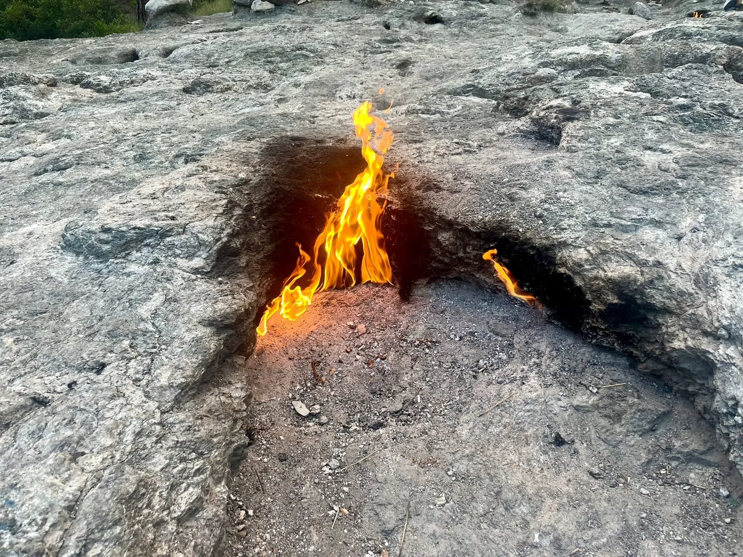 Flames burning directly out of bare rock on a hillside.
