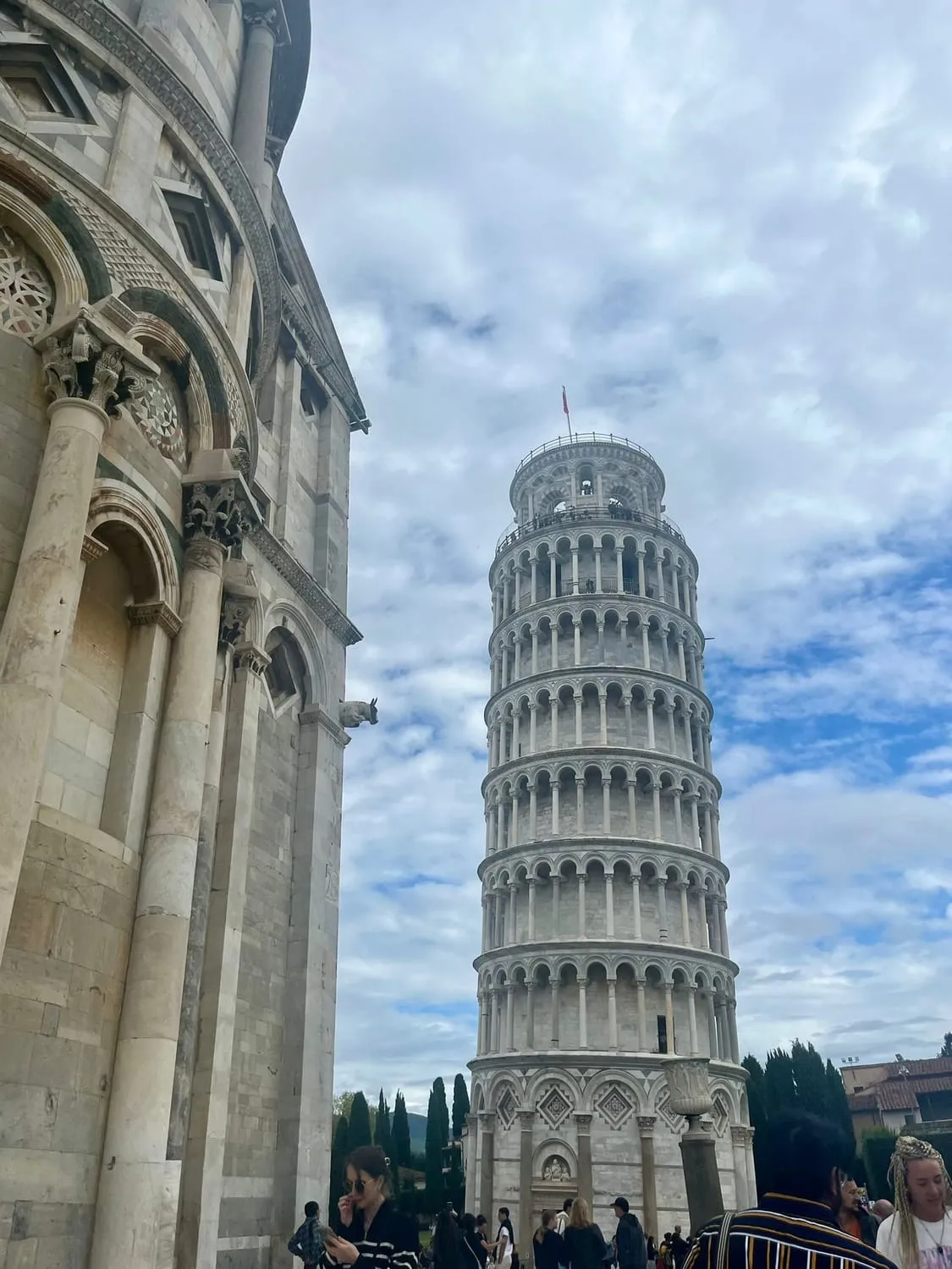 A leaning bell tower beside a marble cathedral front.