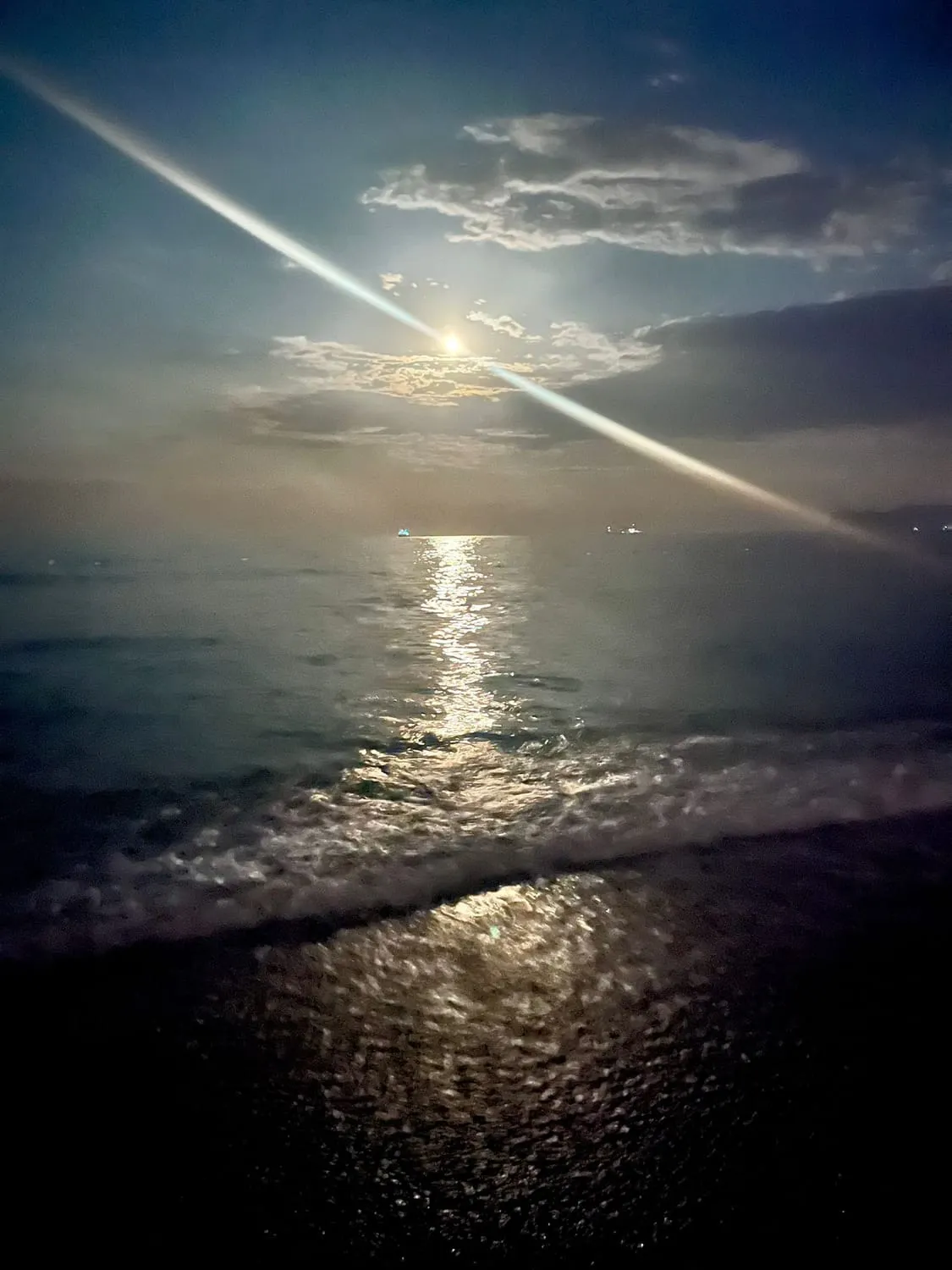 Moonlight laid in a bright path across dark water at night.