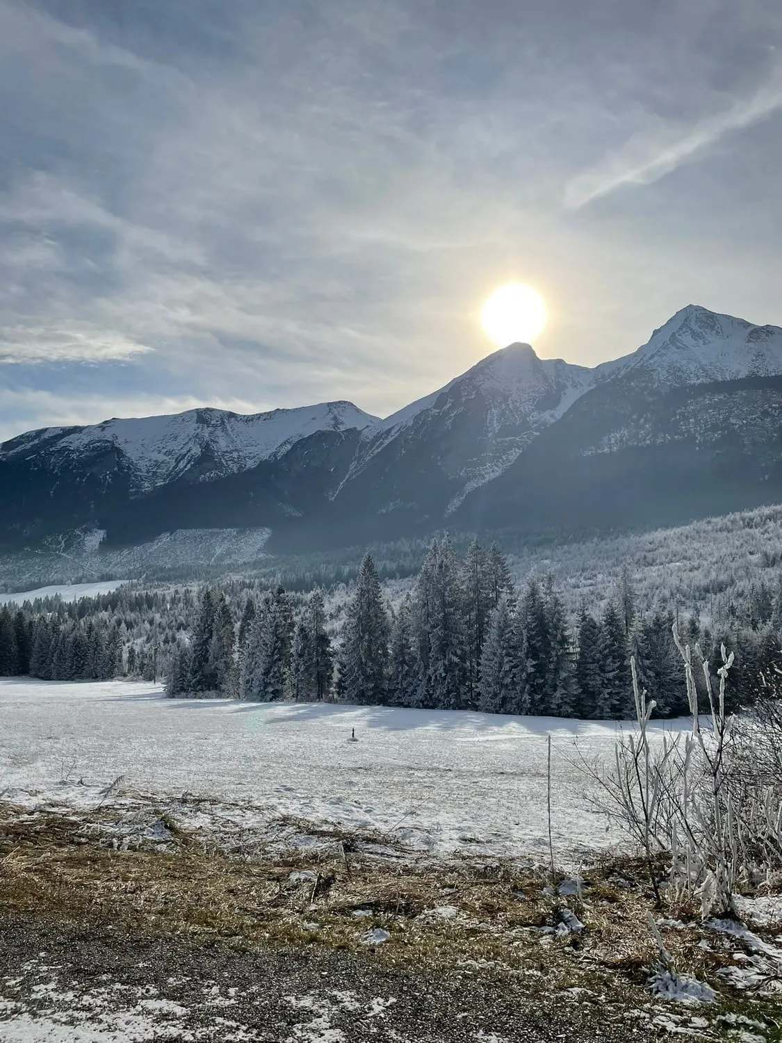 A bright moon low over snow covered mountains and a frozen field.