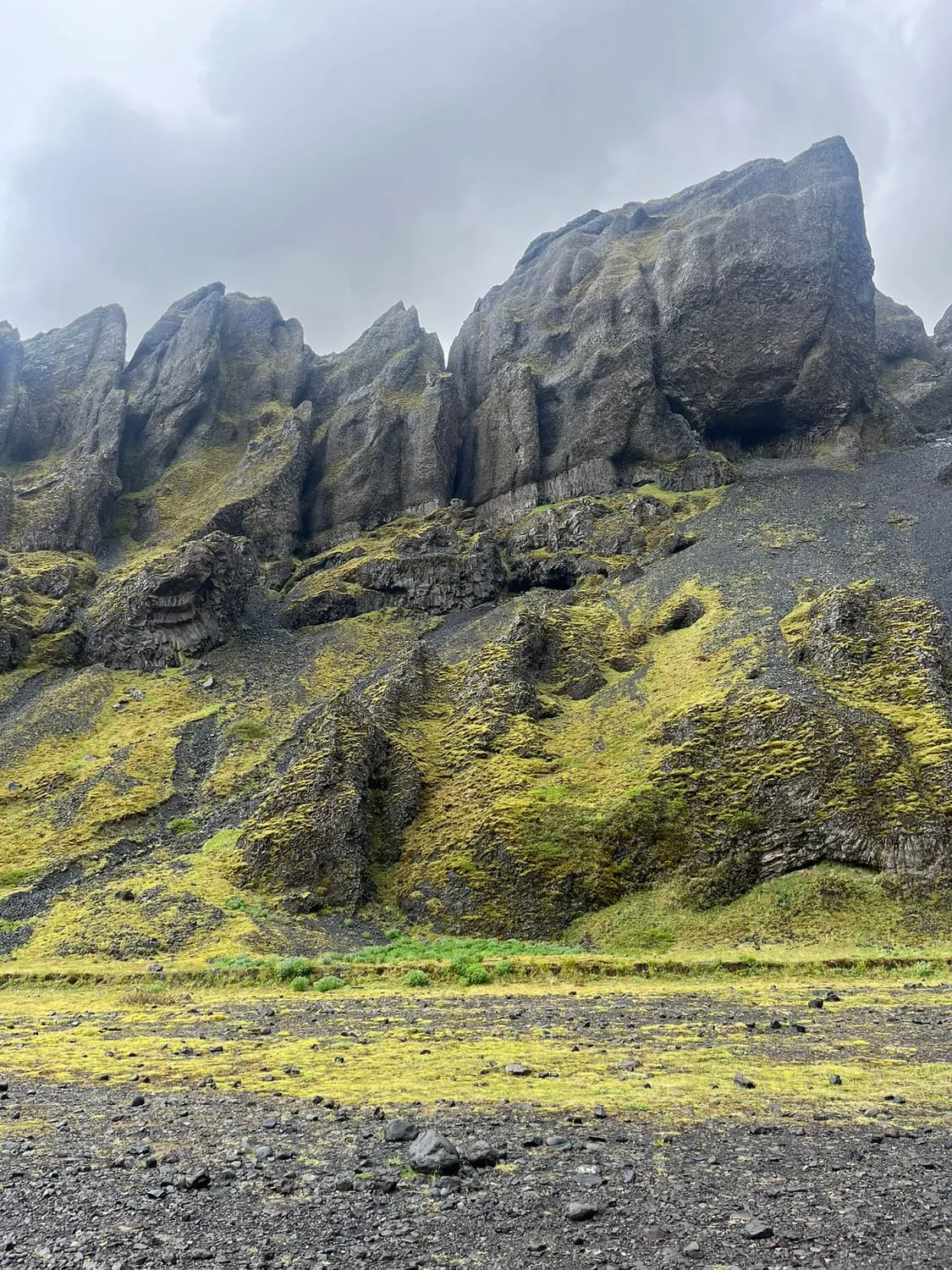 Moss covered lava crags rising from a flat green plain.